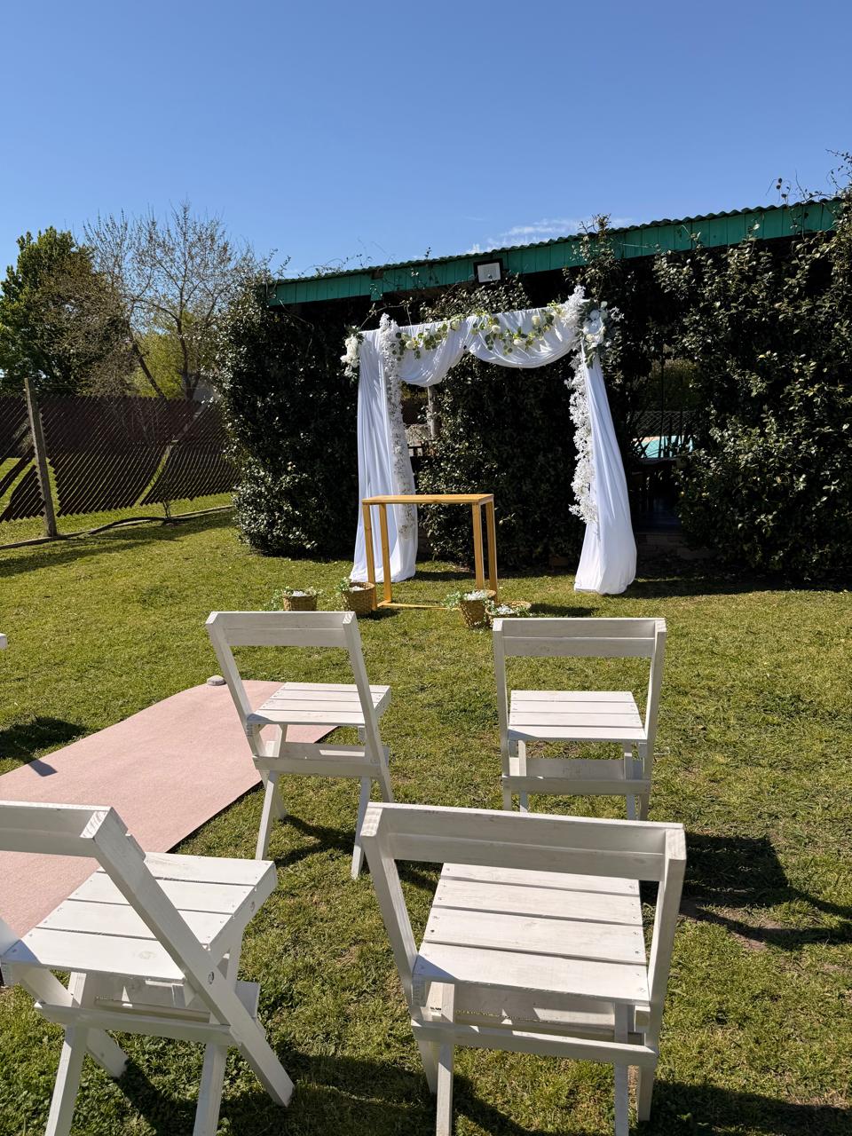Altar con telas blancas y flores en el parque, con sillas para la ceremonia
