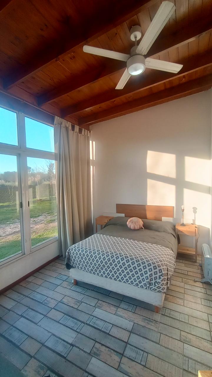 Dormitorio con cama matrimonial, ventanal al parque y techo de madera