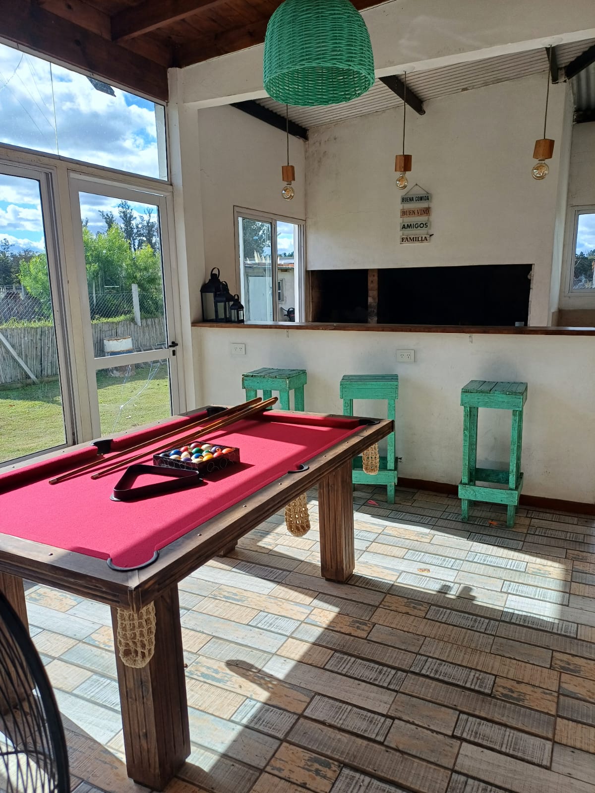 Mesa de pool de paño rojo junto a la barra y parrilla cubierta de Quinta Entre Nosotros Luján